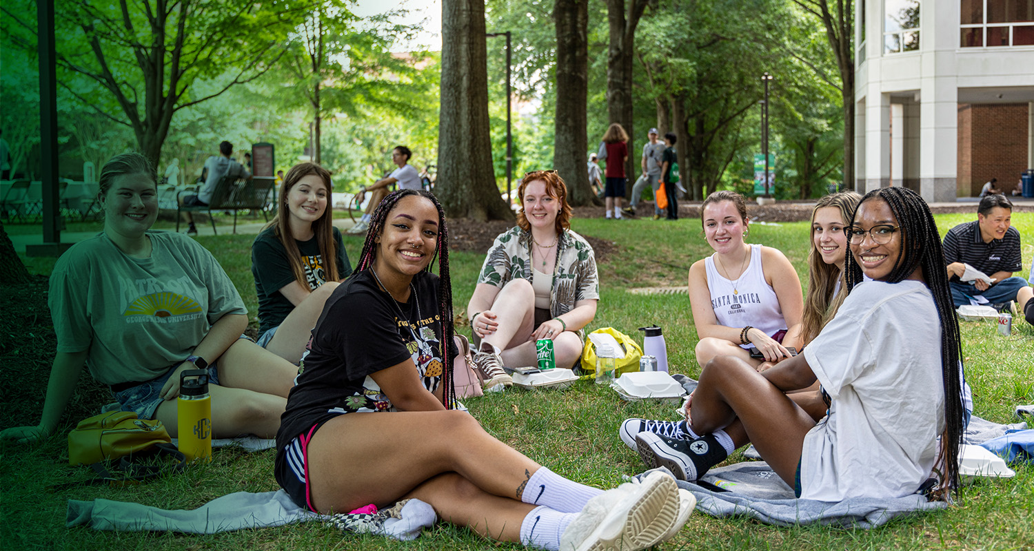 A group of 番茄视频 students relax together in the grass on the Fairfax Campus.