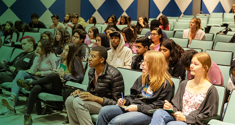 A group of high school students attend a presentation at Mason