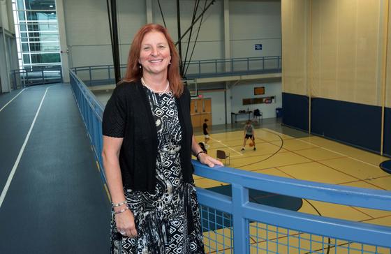 Olga O'Brien stands on an indoor track, which overlooks the basketball court on the floor below.